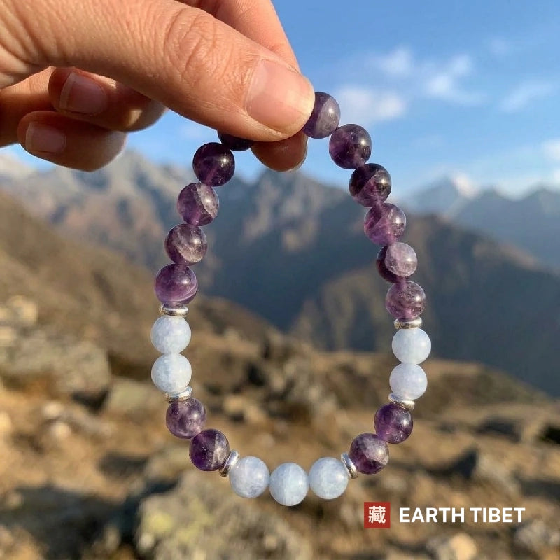Amethyst aquamarine stretch bracelet held up in front of mountains