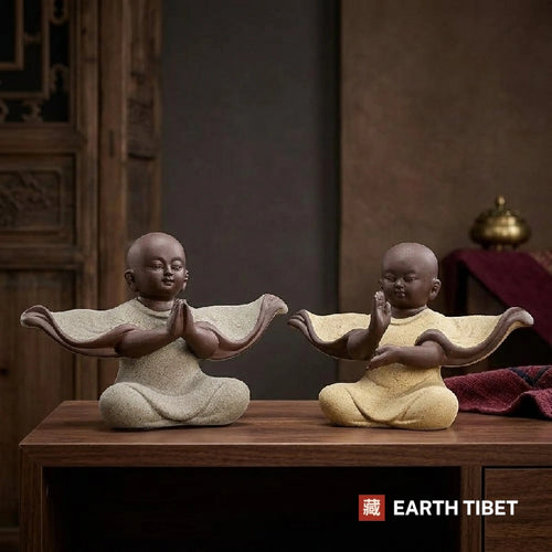 Two baby monk statues facing each other on a wooden console, sleeves sweeping out sideways