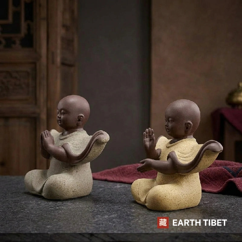 Baby monk statue with flowing sleeves, seated with palms together