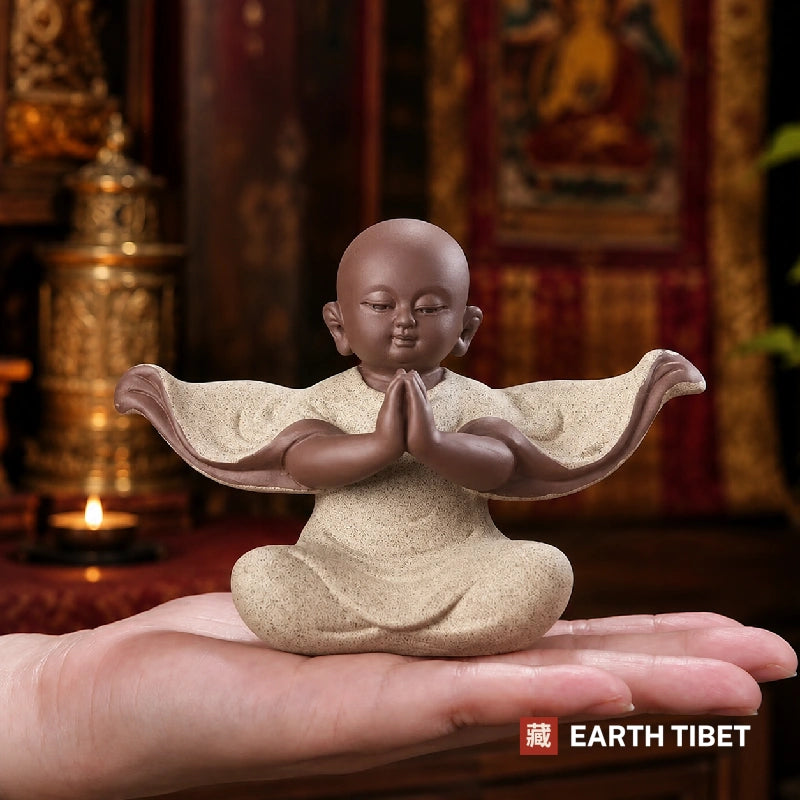 Baby monk statue showing the pale grainy robe against the darker unglazed clay