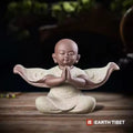 Pale stone baby monk statue with both palms together in anjali, sleeves spread wide
