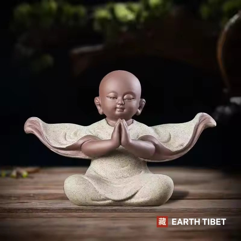 Pale stone baby monk statue with both palms together in anjali, sleeves spread wide