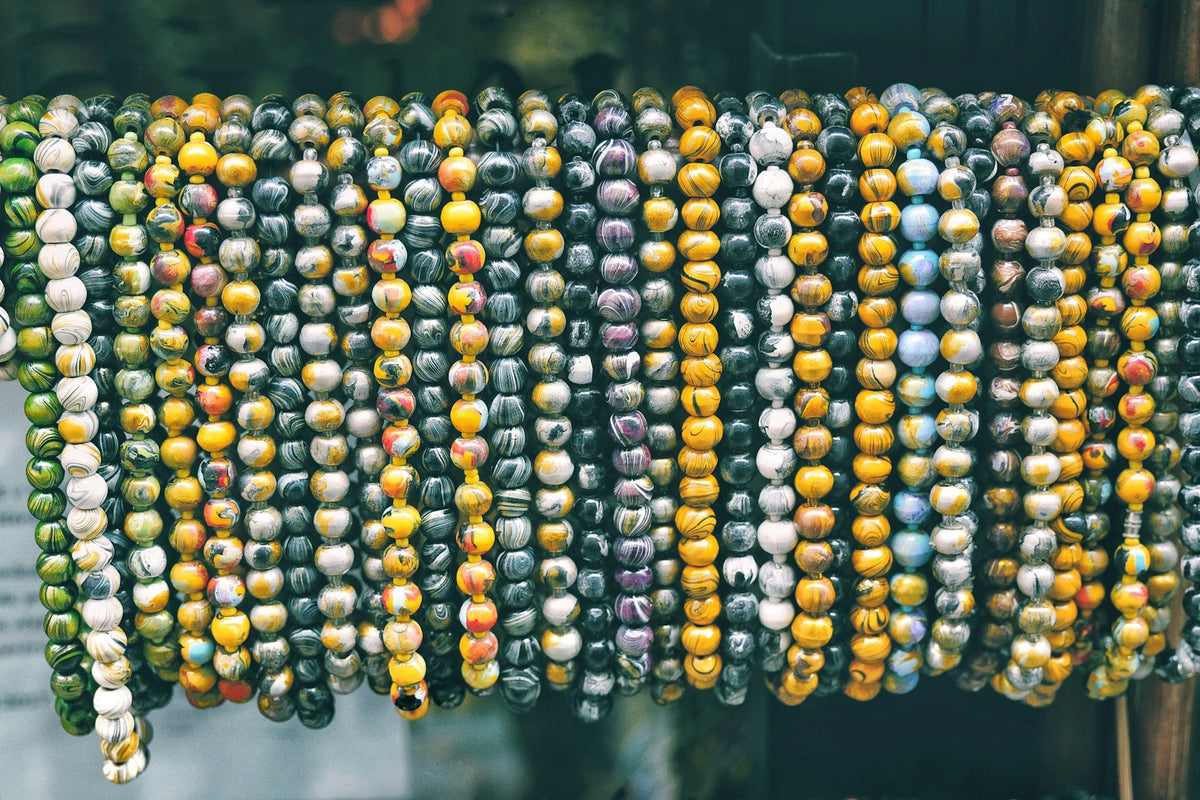 Strands of natural stone prayer beads hanging side by side, each bead patterned differently