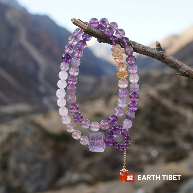 Long amethyst and citrine strand hanging from a branch, carnelian drop below