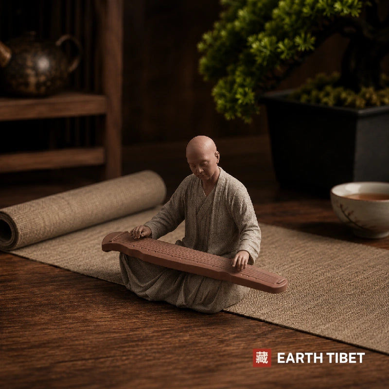 Ceramic monk statue seated playing a guqin zither on a tea table