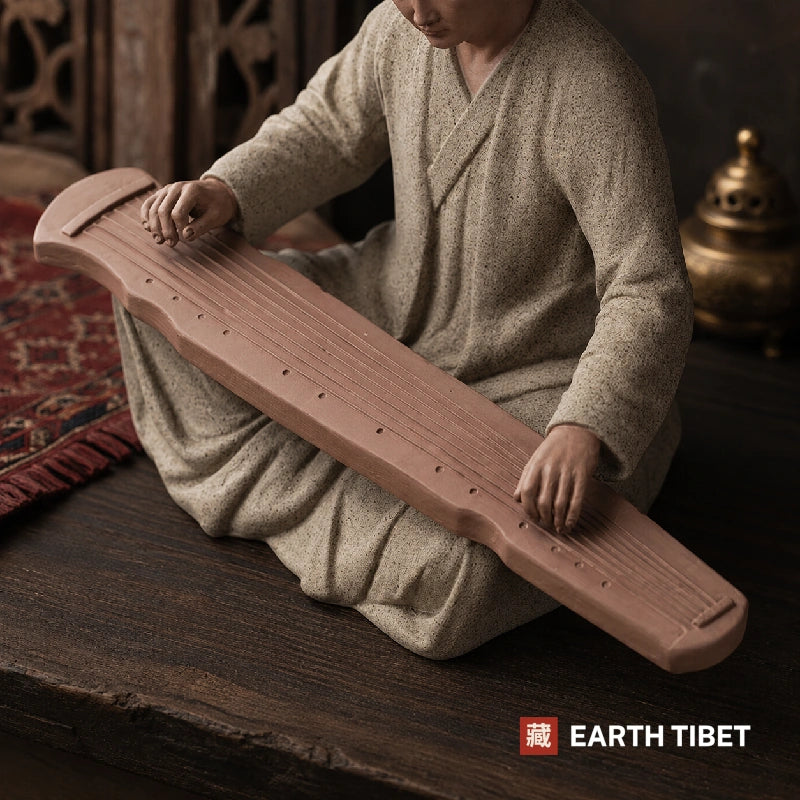 Scholar monk statue in a muted blue robe shown on a shelf