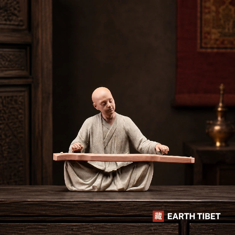 Chinese scholar monk statue styled beside books and a tea set