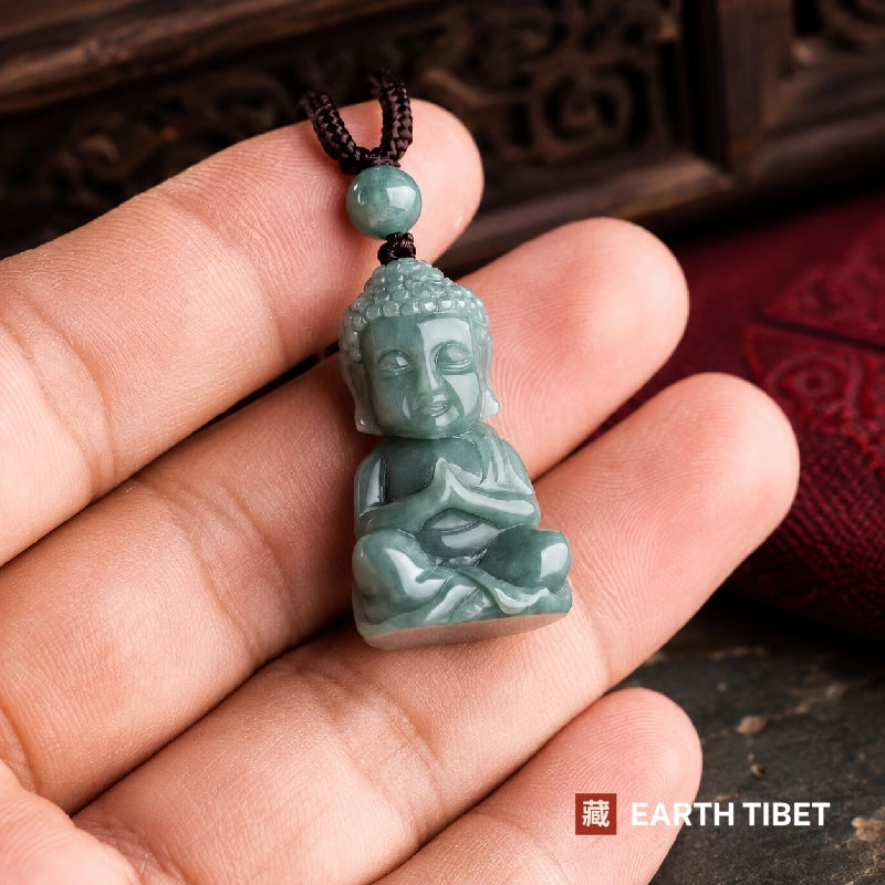 Jadeite Buddha pendant held between two fingers, showing its size and the depth of the carving