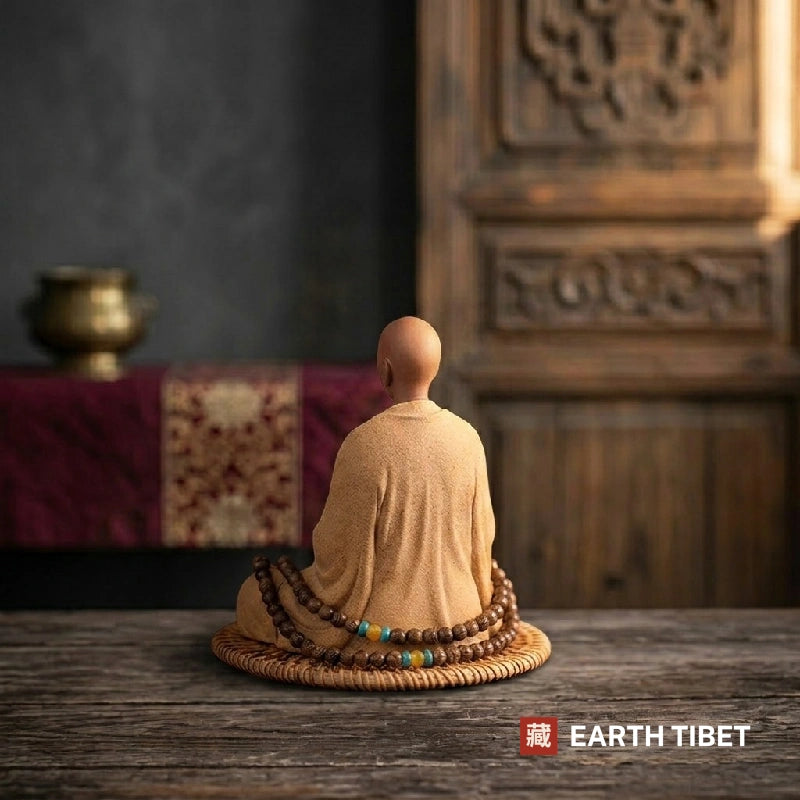 Ceramic meditating monk statue seated on a rattan mat