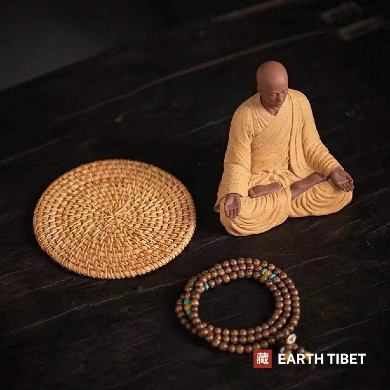 What is included: ceramic monk with hands in the lap, woven rattan mat and a mala