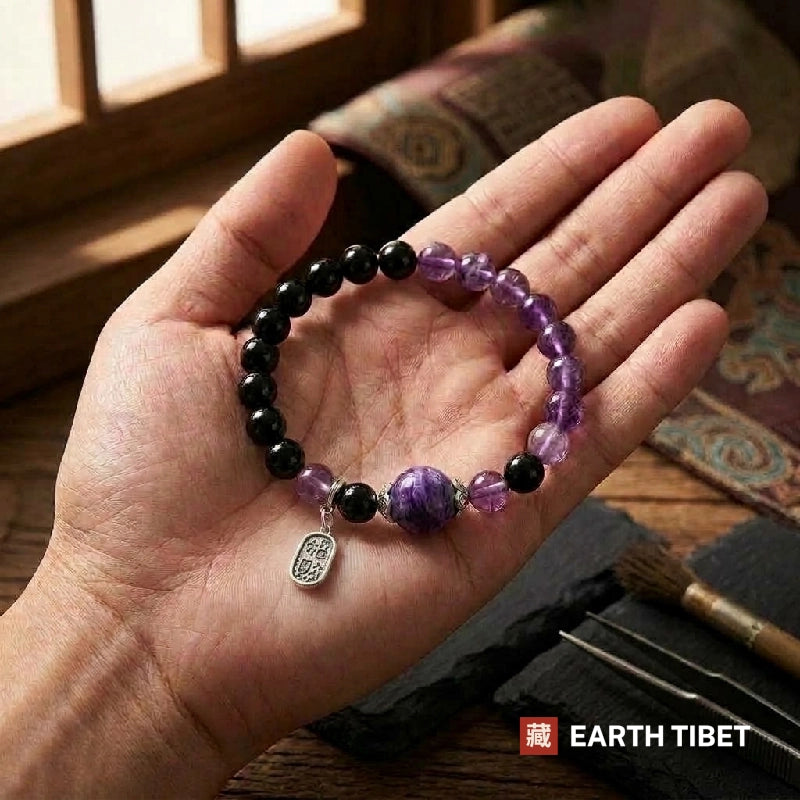 Bracelet lying in an open hand, black obsidian on one side and amethyst on the other