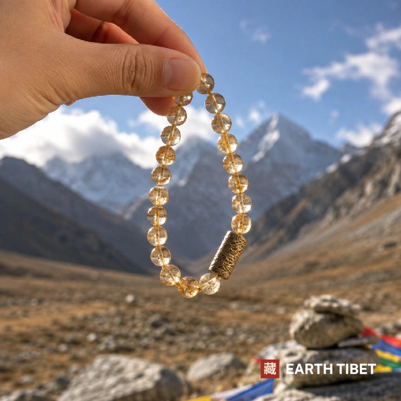 Citrine bracelet held against the Himalaya with a mani stone cairn and prayer flags behind
