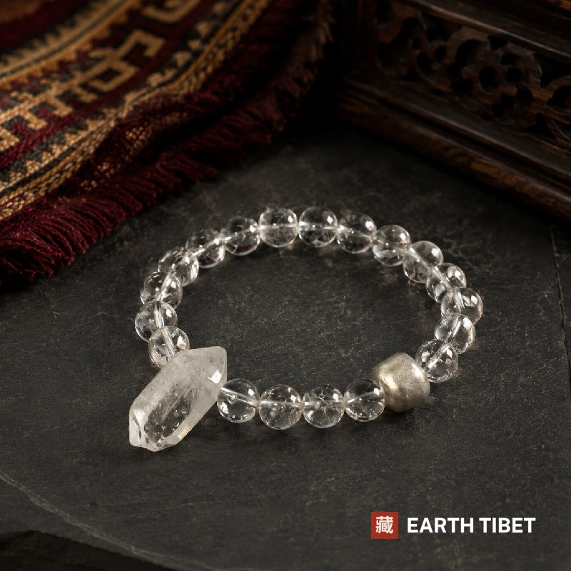 Clear quartz bracelet laid in a loop on slate, the raw point at the front
