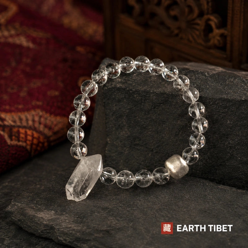 Clear quartz bracelet on a slate ledge with a red carpet and carved panel behind