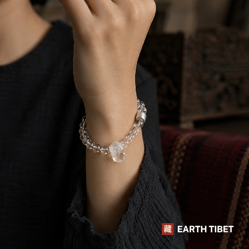 Clear quartz bracelet worn on a wrist against a black textured top