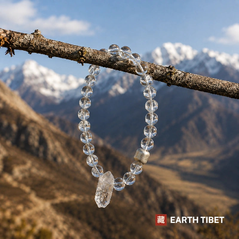 Clear quartz bracelet hanging from a lichened branch above a Himalayan valley