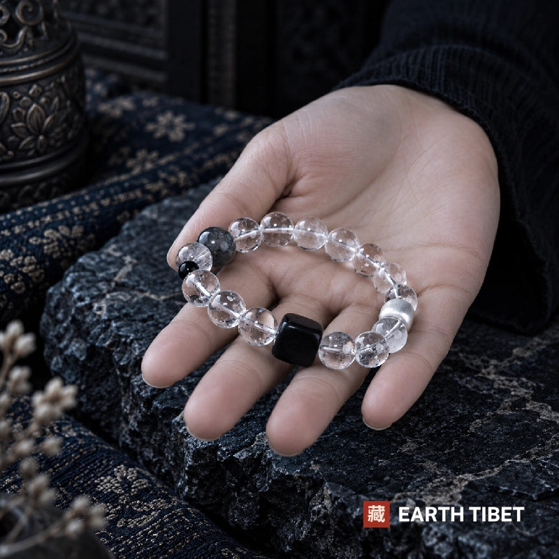 Clear quartz, obsidian and ebony bracelet held in an open palm for scale