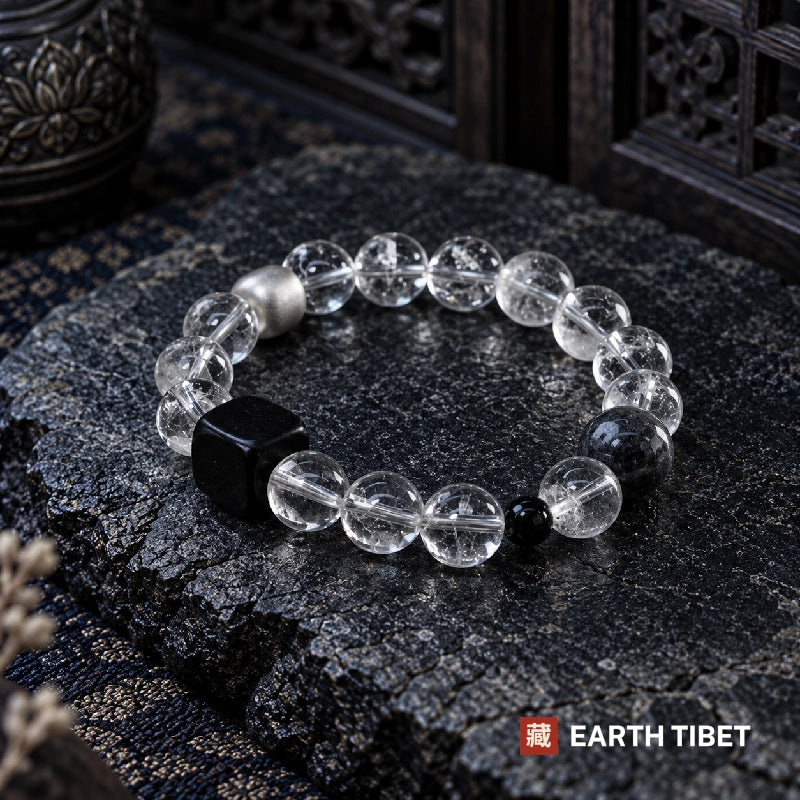 Clear quartz beads showing internal veiling beside the matte ebony cube