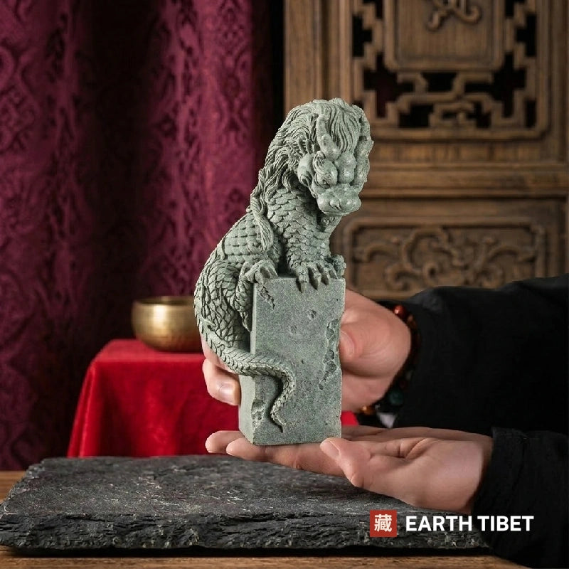 Coiled dragon guardian statue in sandstone displayed on a desk