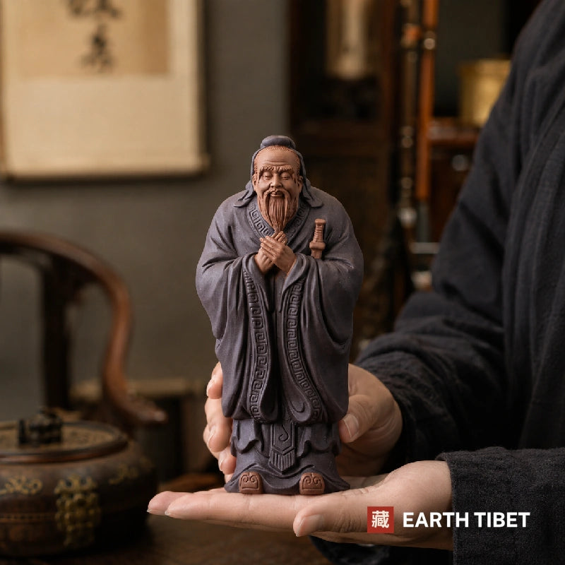 Confucius ceramic statue photographed against carved wood and brass