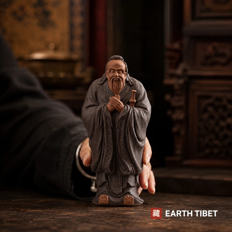 Confucius statue with a hand behind it to show its size, about eighteen centimetres tall