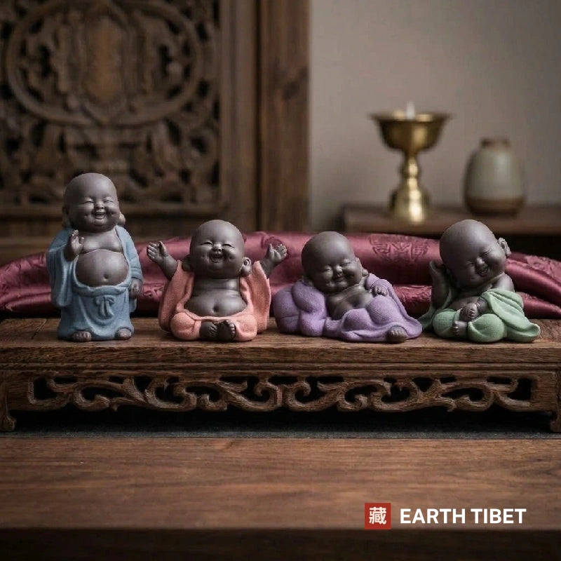 Four baby laughing Buddha tea pets in blue, coral, purple and green robes on a wooden tray