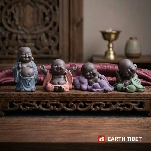 Four baby laughing Buddha tea pets in blue, coral, purple and green robes on a wooden tray