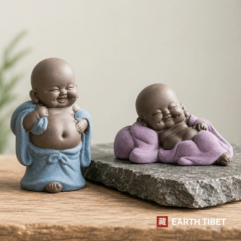 Blue standing baby Buddha holding his robe open beside the purple reclining one