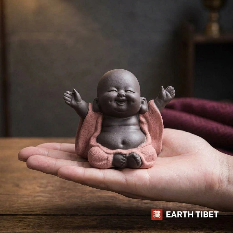 Coral baby laughing Buddha tea pet held in a cupped palm for scale