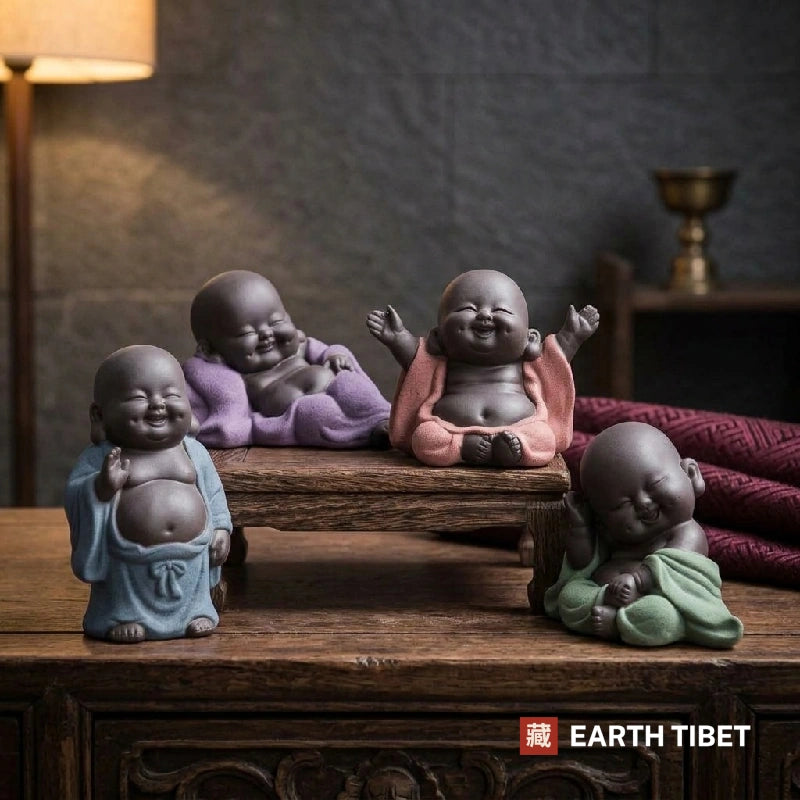 Four purple clay baby Buddha tea pets on a tea table by lamplight