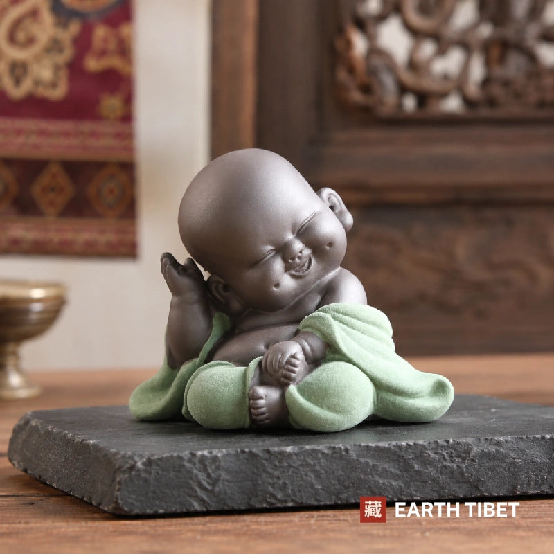 Thinking baby laughing Buddha in a green robe, hand beside his cheek
