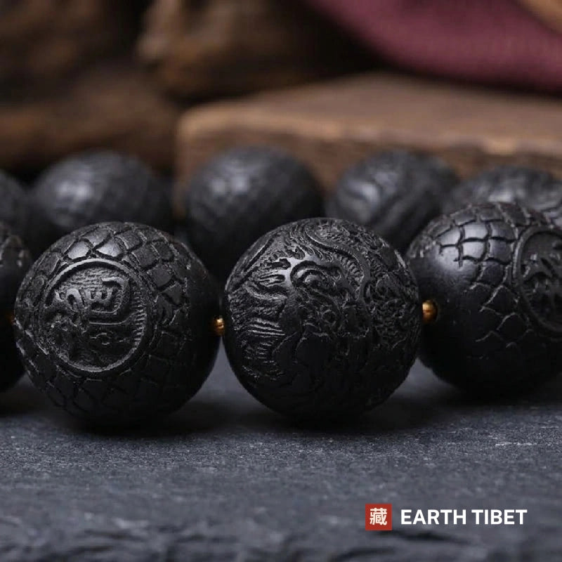 Carved ebony bead showing a dragon in relief over a dragon-scale ground