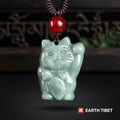 Pale green jadeite fortune cat pendant on a braided cord with a red agate bead above it