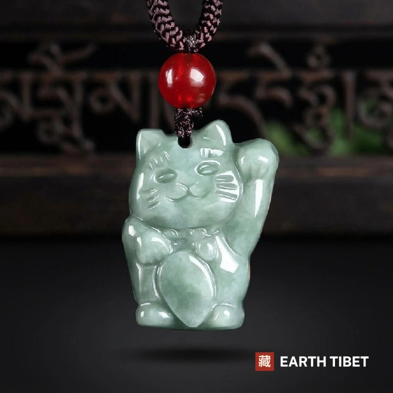 Pale green jadeite fortune cat pendant on a braided cord with a red agate bead above it