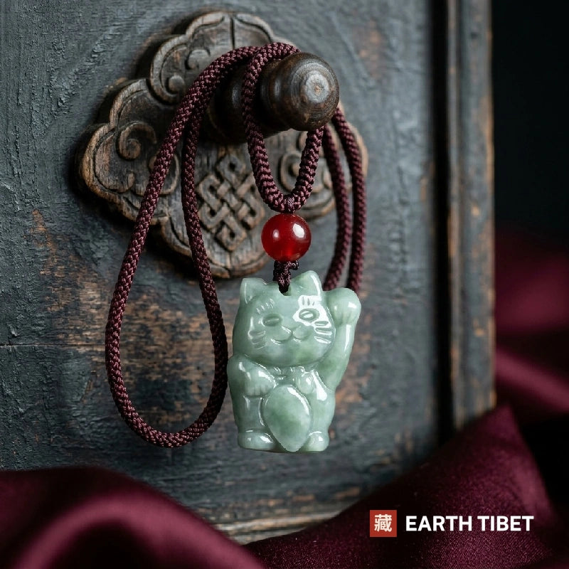 Jadeite fortune cat necklace hung by its looped cord on a carved wooden door
