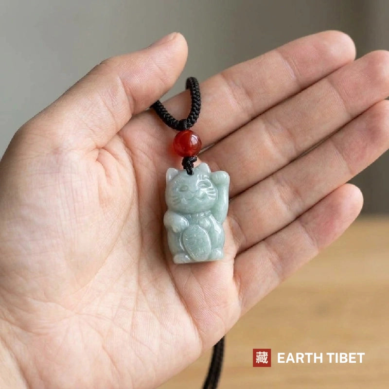 Jadeite fortune cat pendant held in an open hand, about two fingers wide