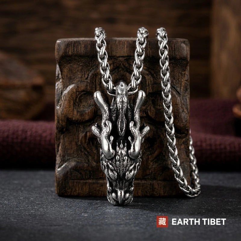 Long narrow dragon head pendant hanging vertically against carved wood