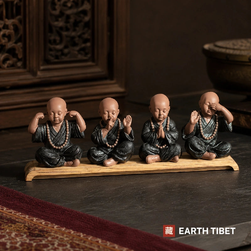 Four ceramic monks on a wooden stand, hear, speak, pray and see no evil, against carved rosewood