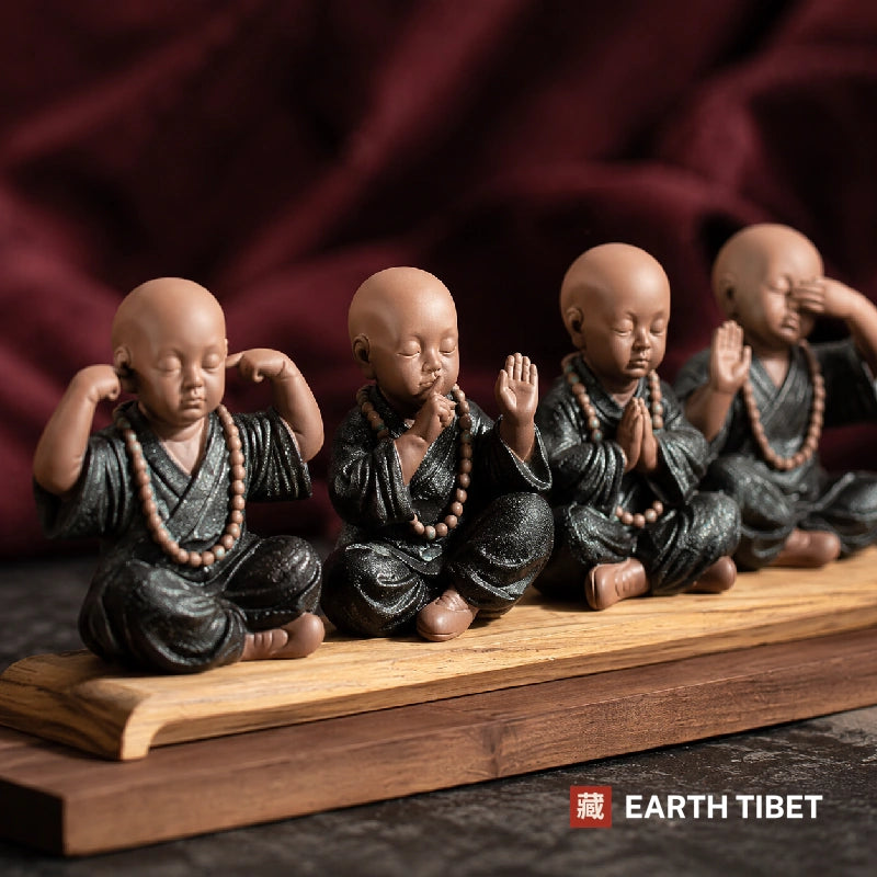 Four monks ceramic set at a low angle against deep red cloth, mala beads at each neck