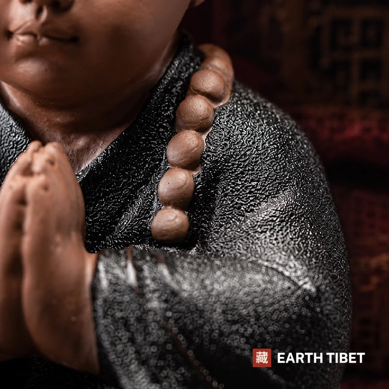 Macro of a ceramic monk's mala beads against the dark speckled glaze of his robe