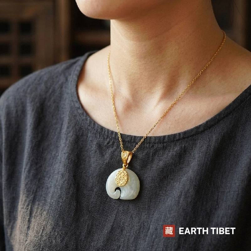 Fu elephant pendant worn at the collar of a grey linen top