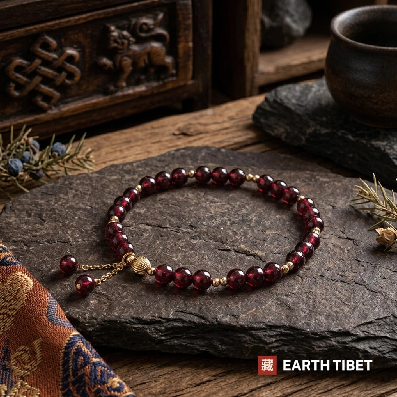 Chinese garnet vitality bracelet on dark slate beside a carved Tibetan chest