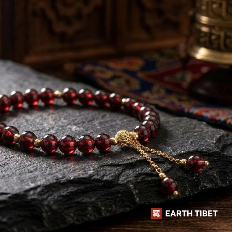 Close view of deep wine red garnet beads with gold-tone spacers and chain dangle