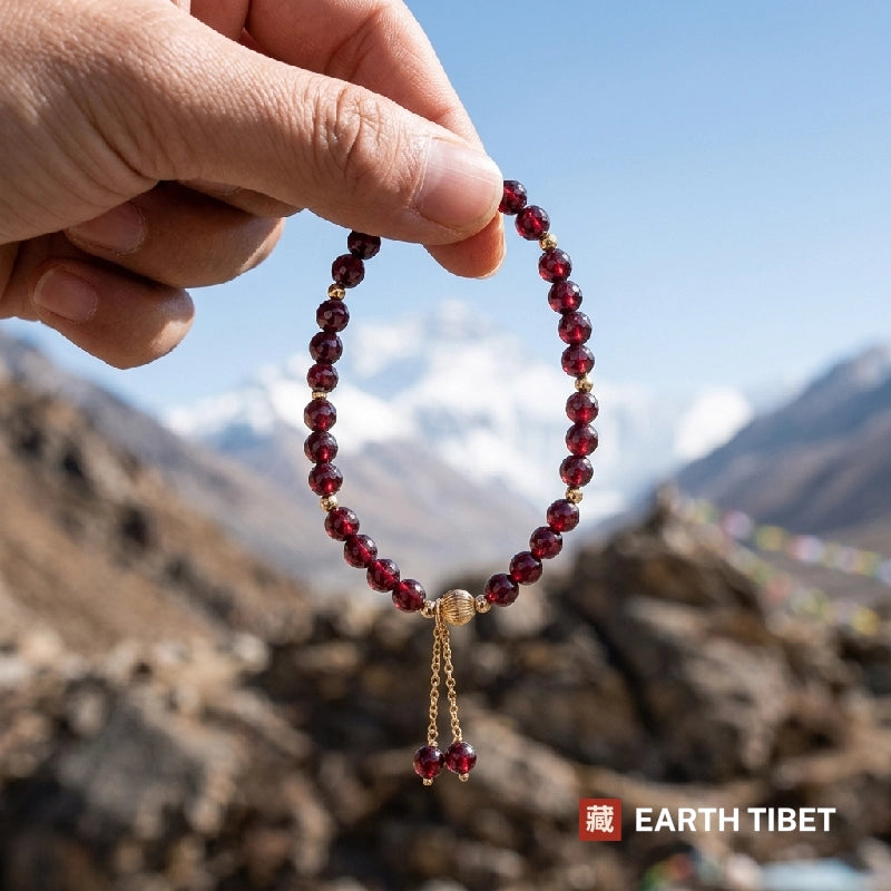 Garnet bracelet held to daylight, beads turning transparent red against Himalayan peaks