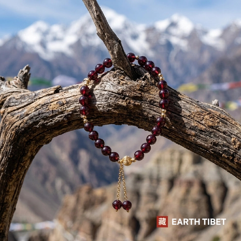 Garnet bracelet hung on driftwood with snow mountains and prayer flags behind