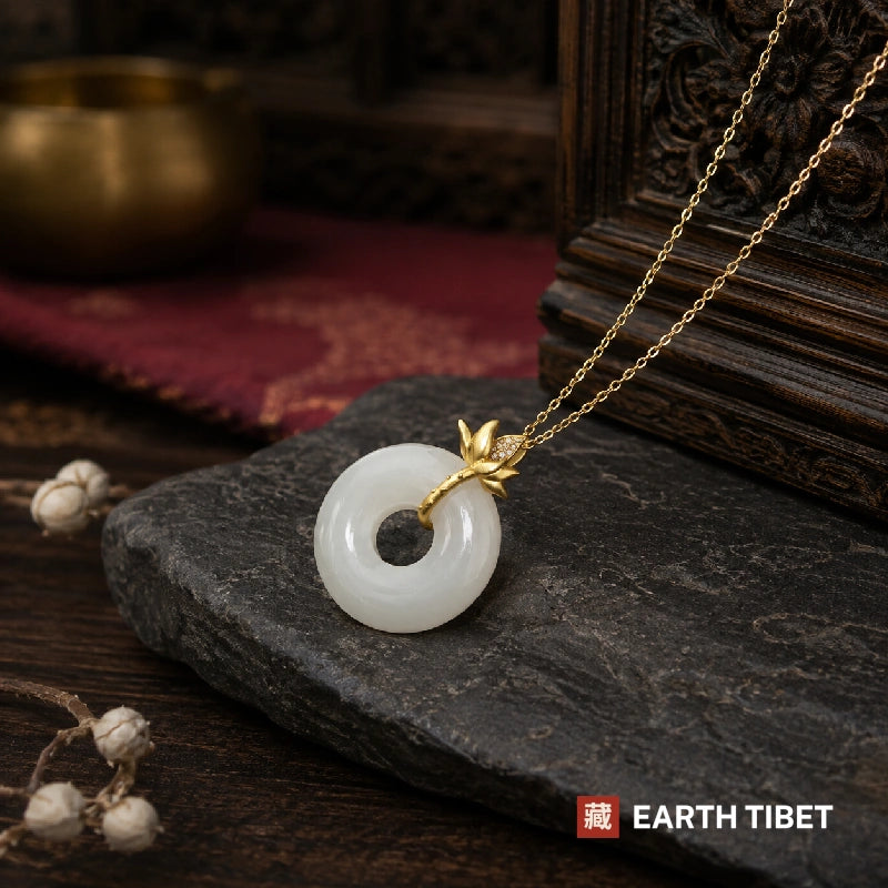 Gold lotus peace agate necklace resting on slate with the chain trailing beside it