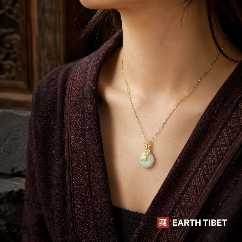 Golden koi jade necklace worn at the collarbone over a maroon embroidered wrap