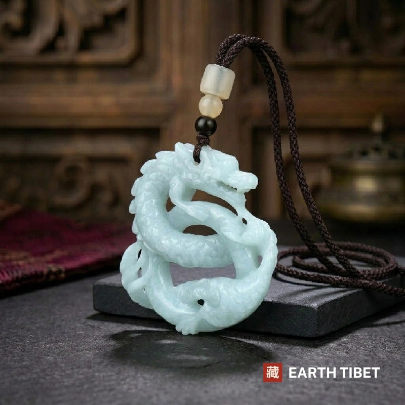 Openwork jade dragon pendant on a braided cord, resting against a black slate slab