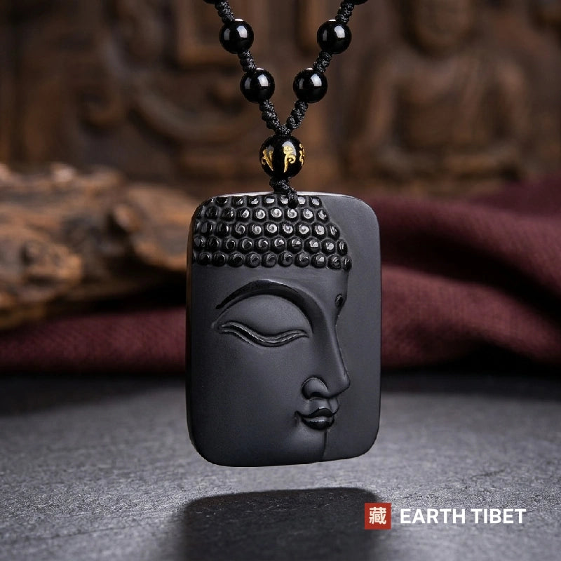 Half-carved obsidian Buddha face pendant showing snail-shell hair curls