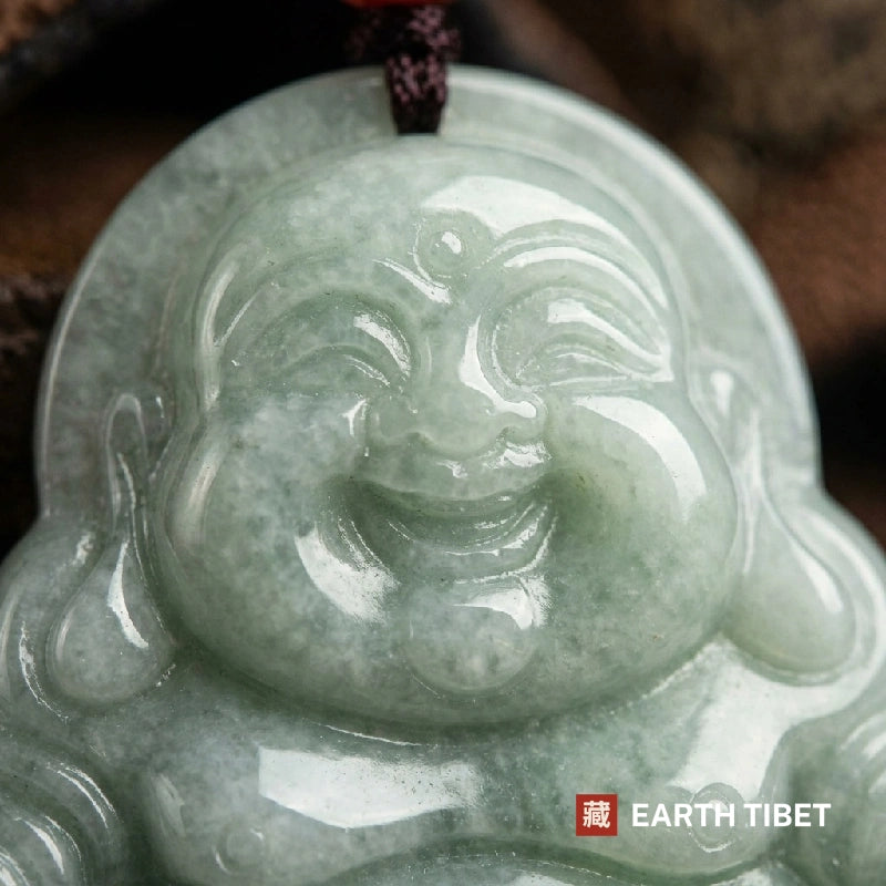 Close view of the laughing Buddha's carved face and long earlobes in pale green jadeite